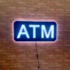 ATM LED Retail ready sign lit during daytime hours against a red brick wall