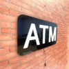 ATM LED Retail ready sign lit during daytime hours against a red brick wall from an angle and not lit