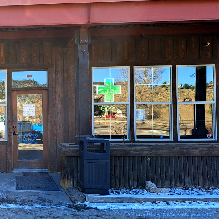 Rocky Mountain Cannabis dispensary with a green cross smoke shop sign hanging in the window in the daylight