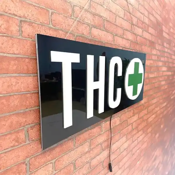 THC with Green cross LED sign hanging on red brick wall