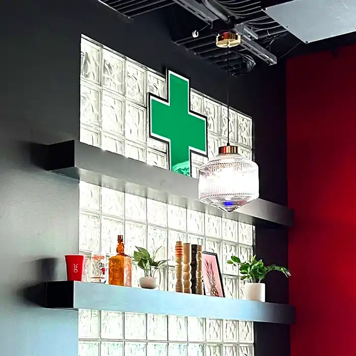 Green Cross LED Sign on the top shelf of a cannabis dispensary, Grasshopper Club, located in Logan Square