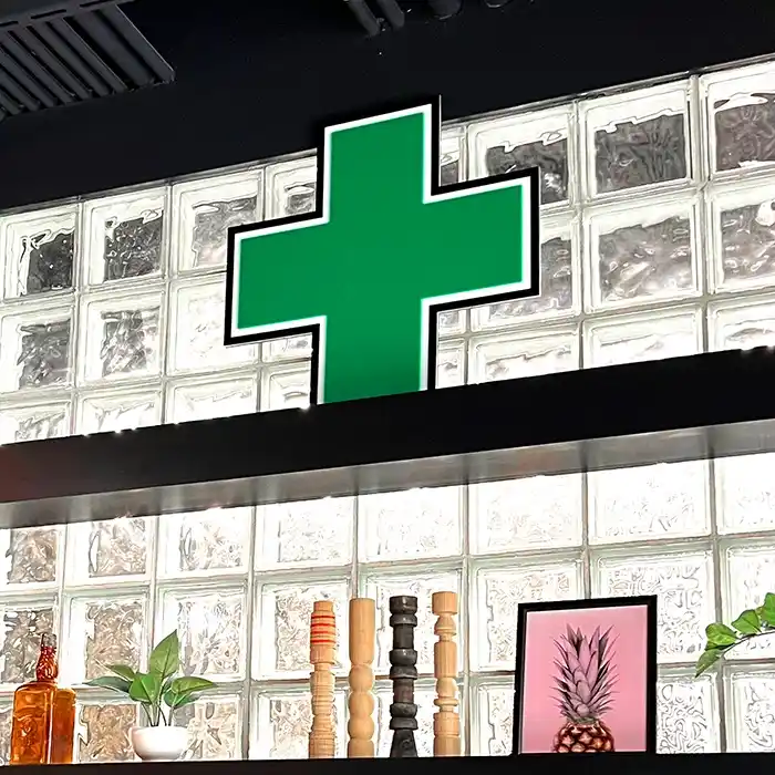 Green Cross LED sign sitting on Grasshopper Club's cannabis dispensary shelf