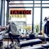 Tattoo Sign hanging on an inside window above an artist working on a client