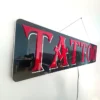Tattoo LED Retail ready sign against a white wall not lit at an angle