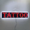 Lit LED Tattoo Sign hanging against a white wall