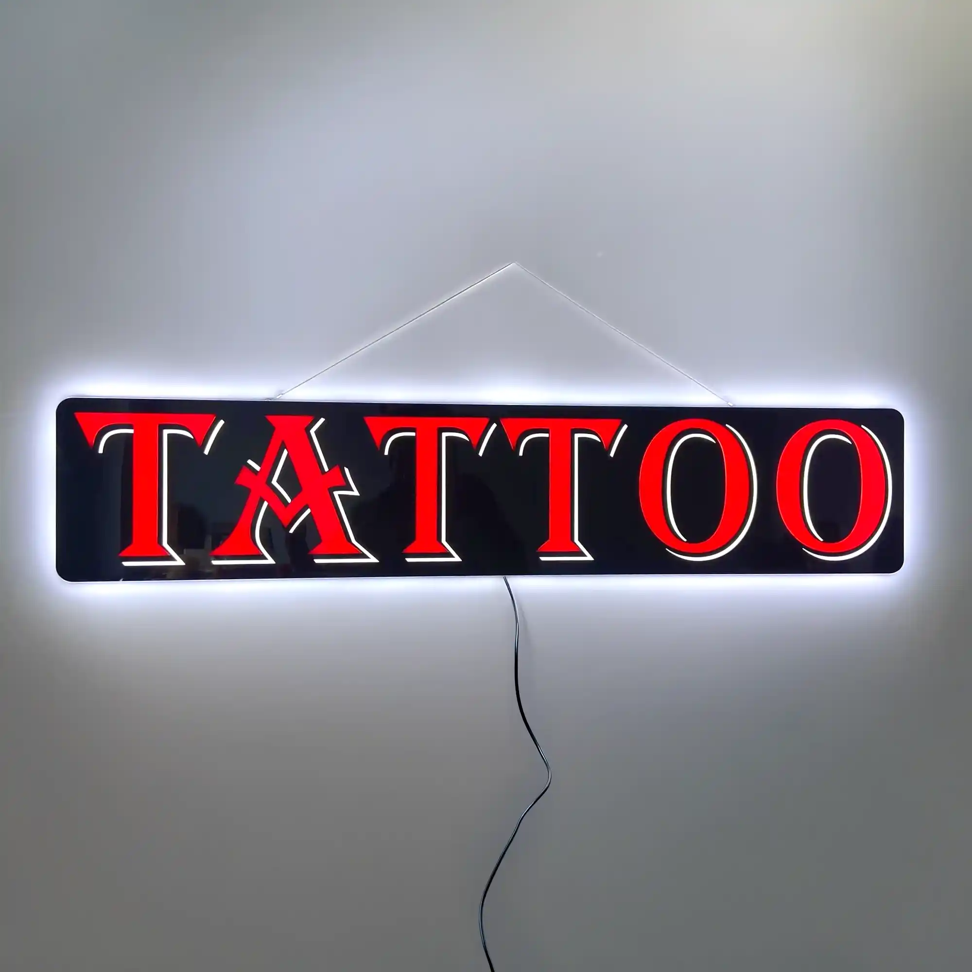 Lit LED Tattoo Sign hanging against a white wall