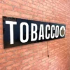 Tobacco LED sign against a red brick wall not lit