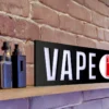 Vape Shop Sign LED sitting on a shelf with vape devices