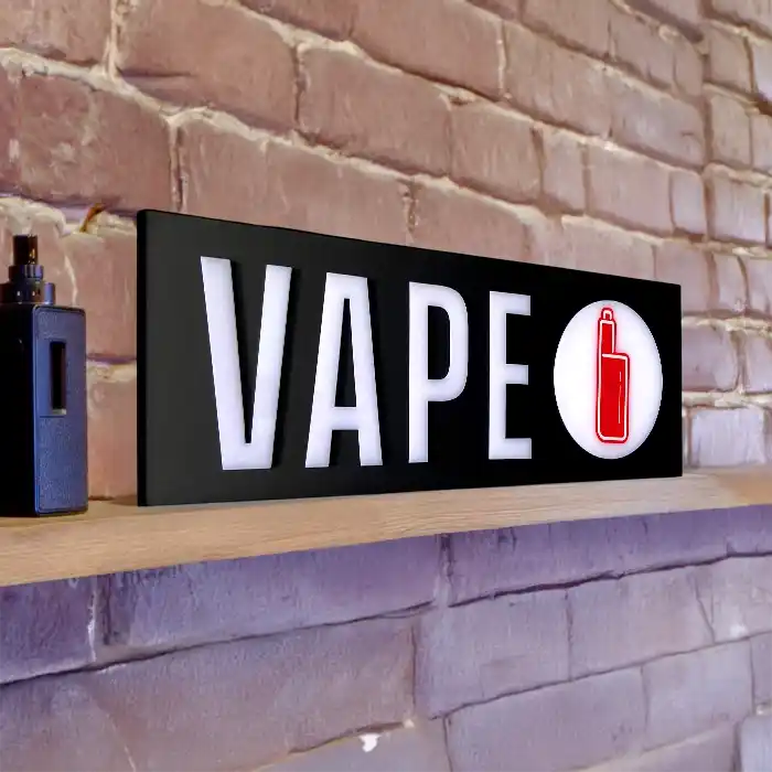 Close-up of an LED vape sign sitting on a smoke shop shelf