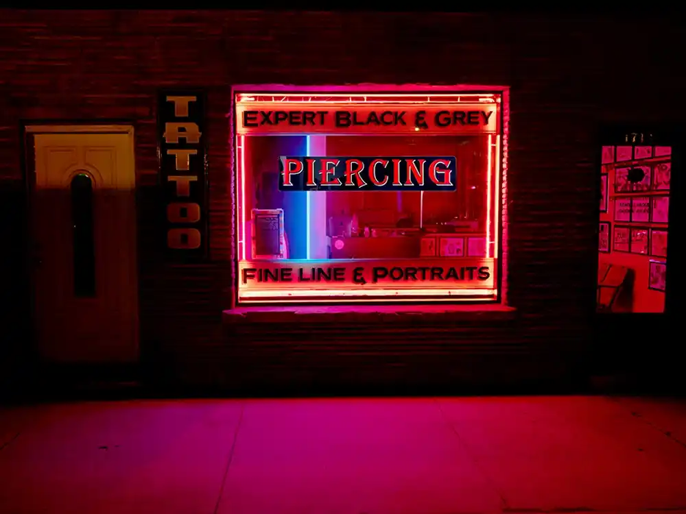 Piercing LED window sign on a tattoo parlor storefront