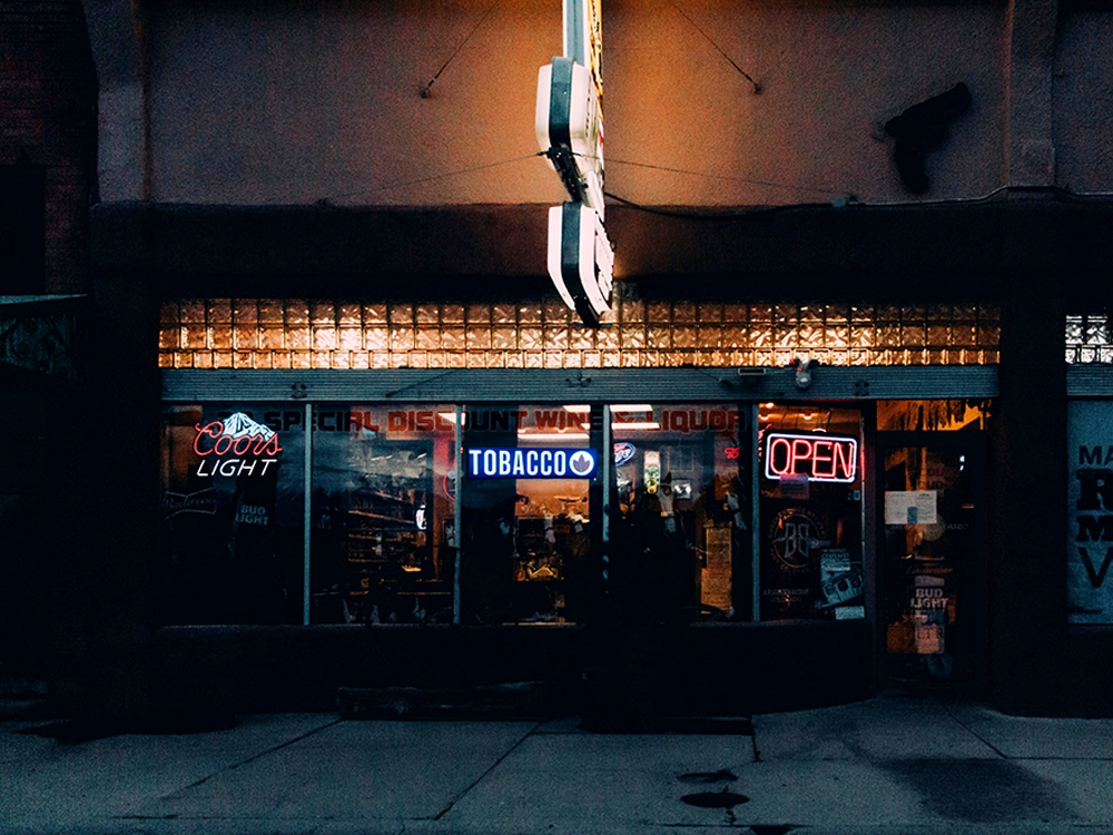 Liquor store with a tobacco sign lit on the front where cigars are sold