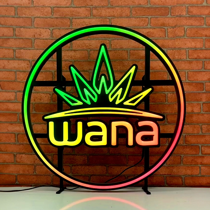 LED neon sign with the word "wana" inside a circular frame, featuring a crown design on top, displayed against a brick wall.