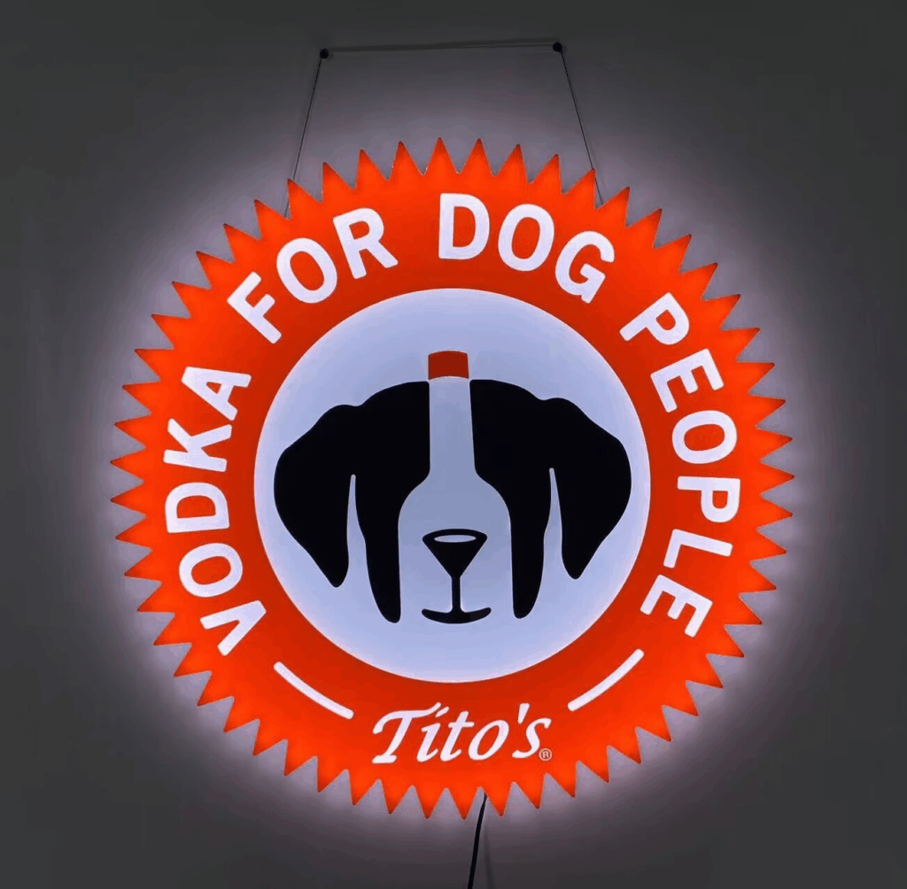 A circular neon sign reads "Vodka for Dog People Tito's" with a dog face graphic incorporating a vodka bottle.